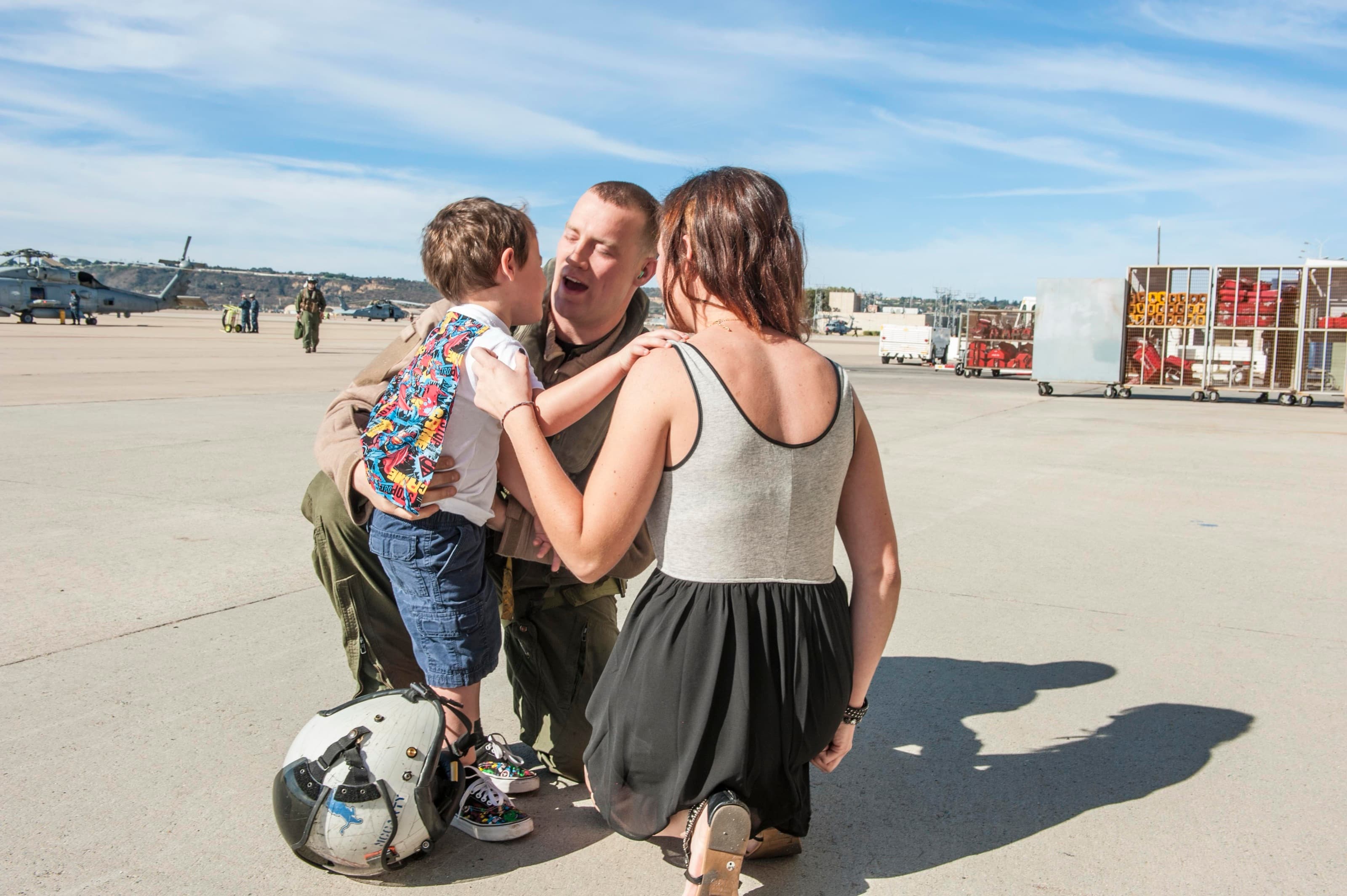 A Navy aircrew member reunites with his wife and son on the flightline